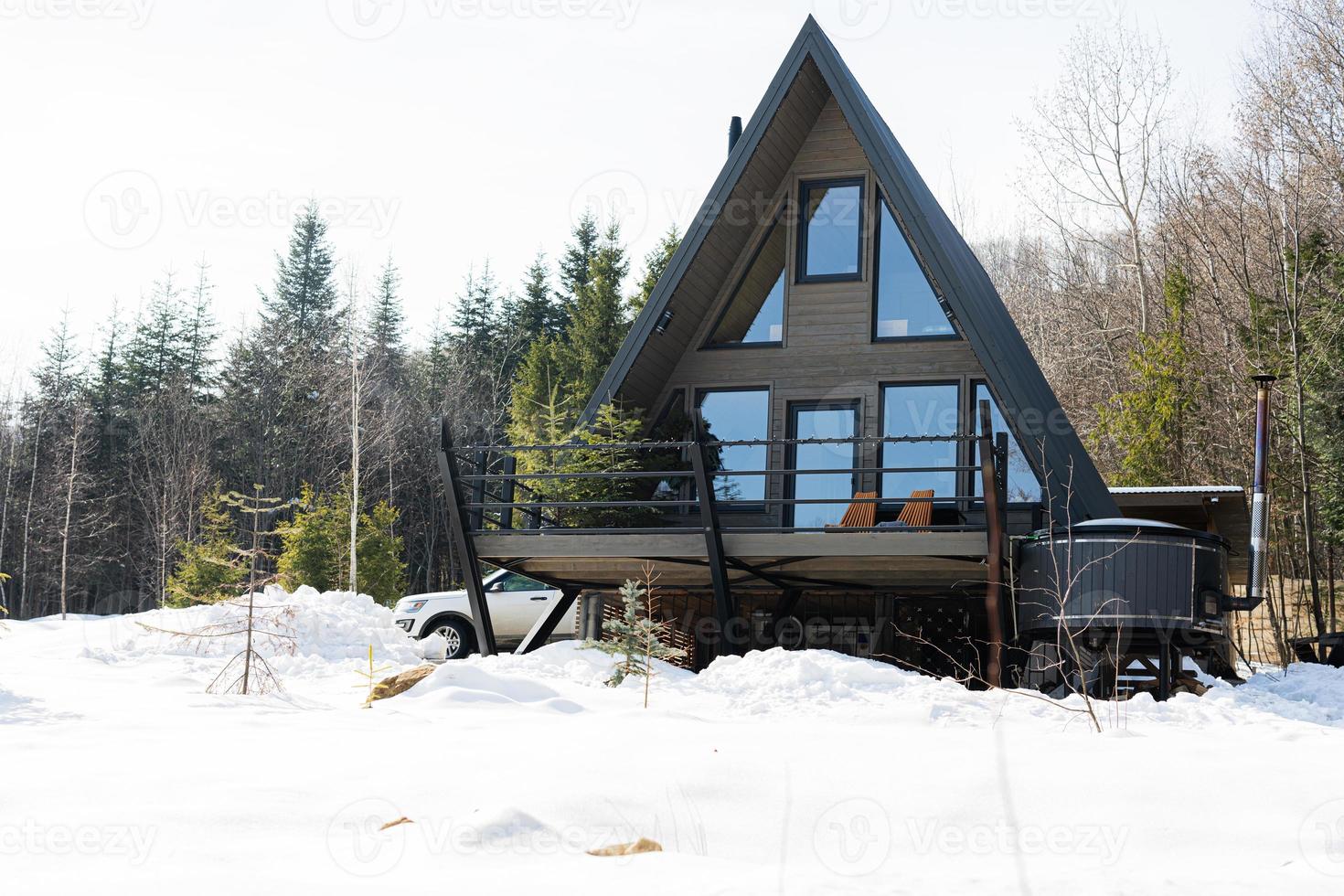 trä- triangel Land mycket liten stuga hus med varm badkar spa och sUV bil i berg. själ helger. foto