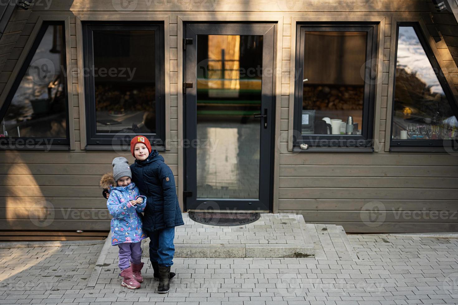 äldre bror kram yngre syster mot Land mycket liten stuga hus. foto