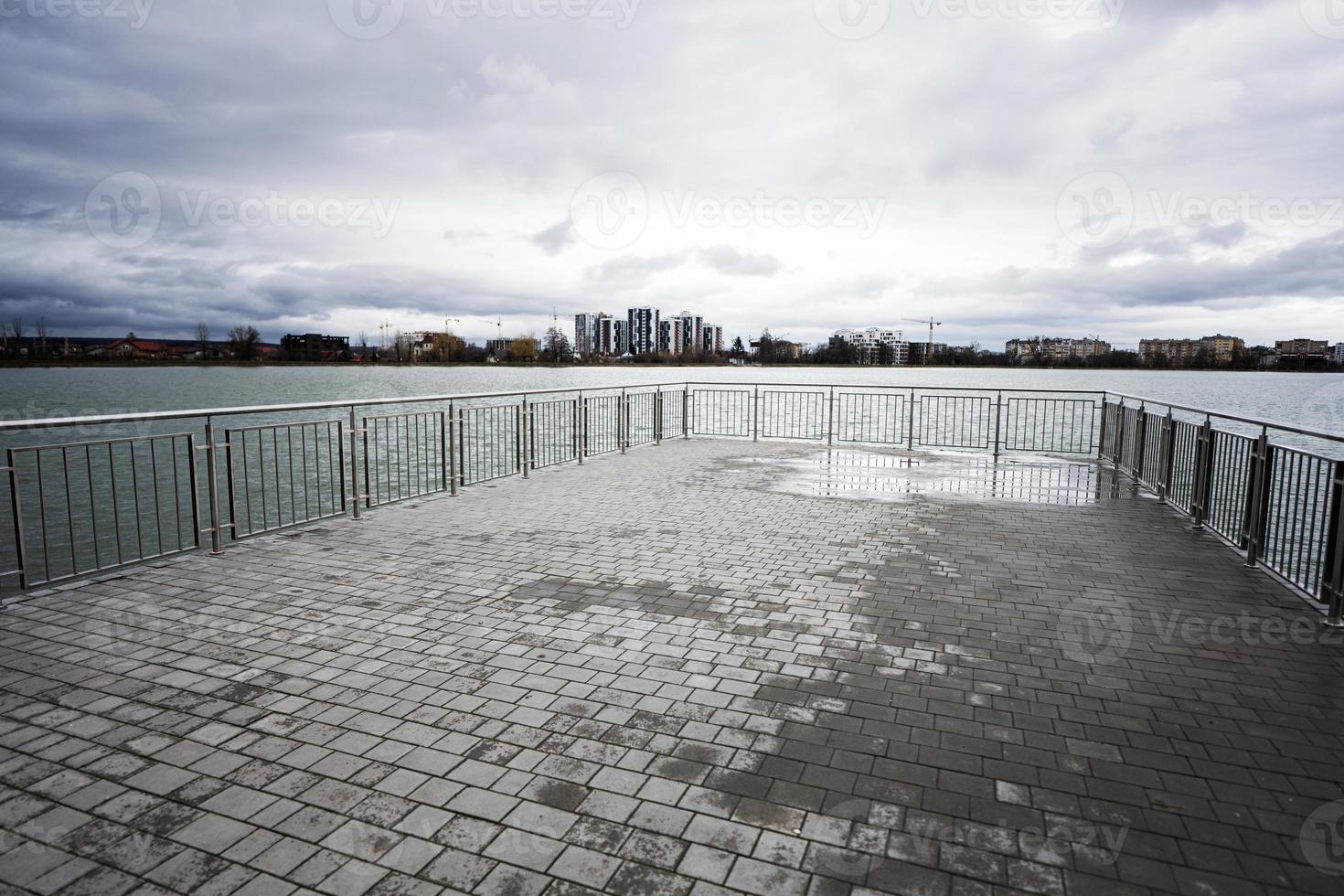 pir av sjö promenad med glas byggnad flervåningshus bosatt hus på bakgrund. foto