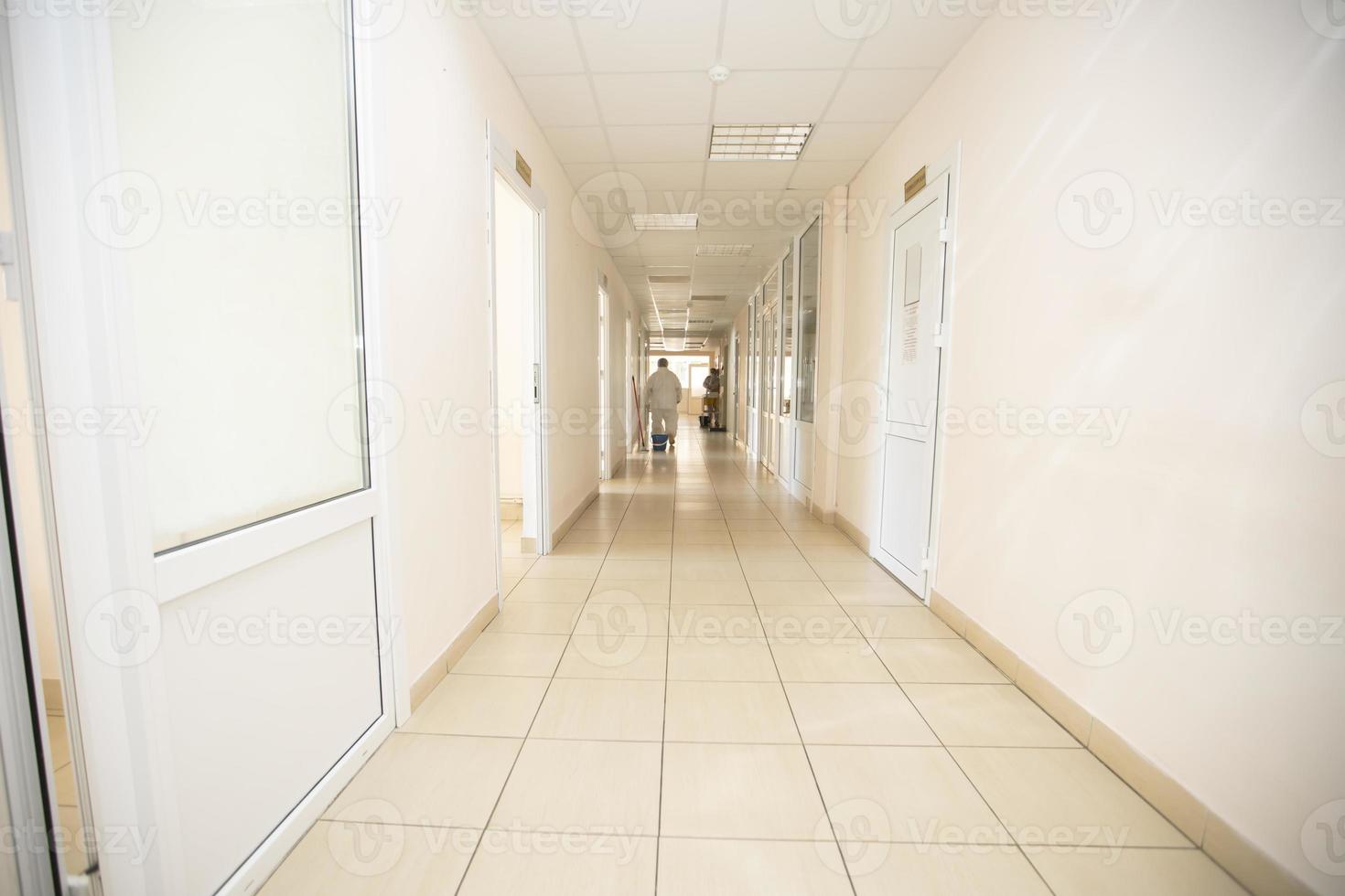 lång sjukhus korridor med en silhuett av en läkare i en skyddande kostym. foto