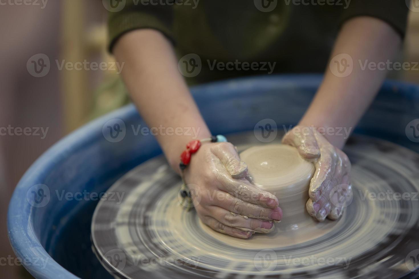 närbild av en krukmakare händer med ett Artikel på en krukmakare hjul. arbetssätt med lera. lera verkstad. hantverk Träning. foto
