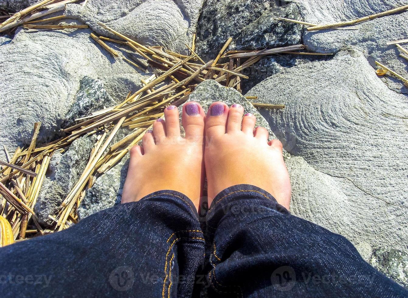 kvinnor flicka fötter med målad naglar i natur på stenar. foto