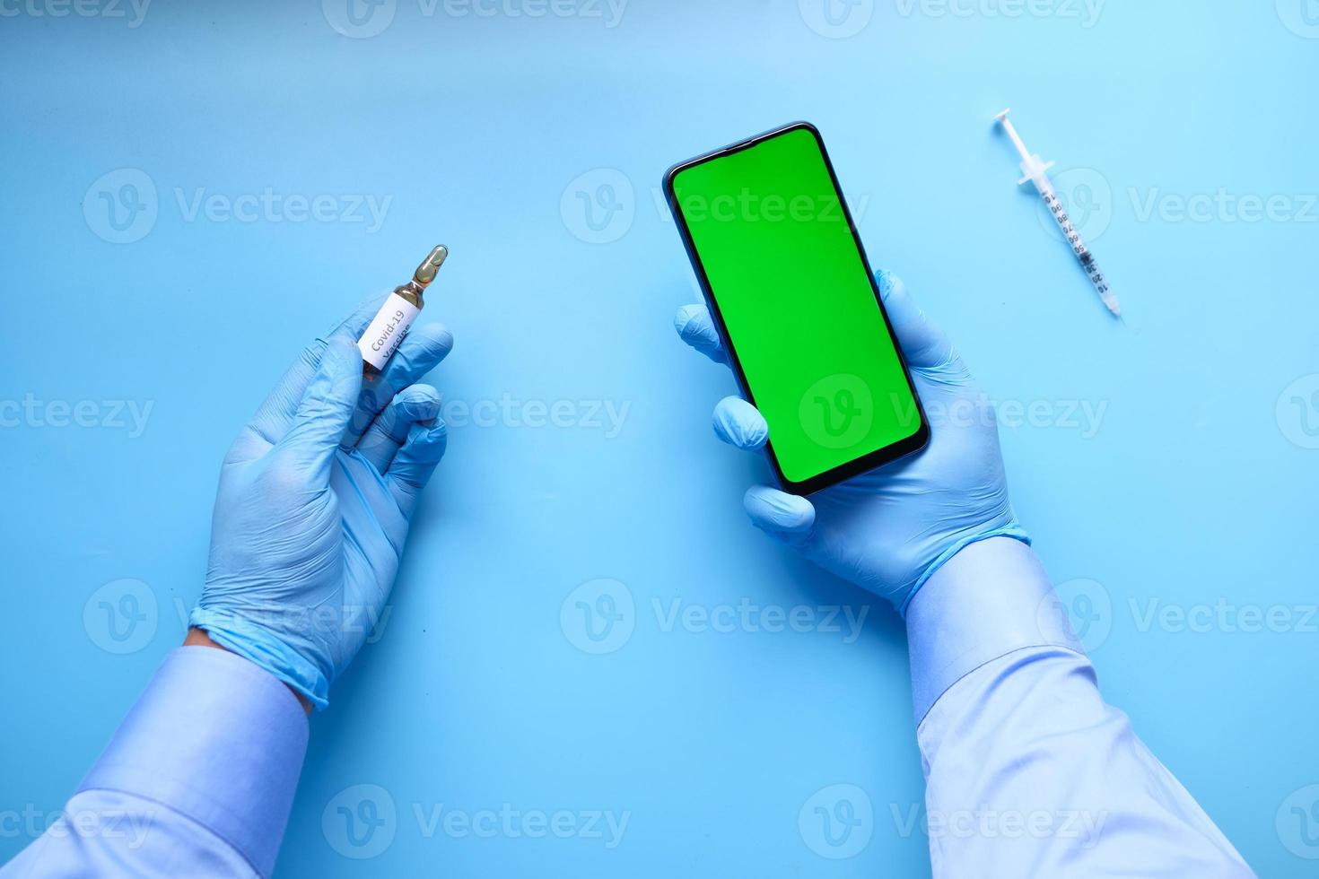 vaccintillförsel med telefonskärm på blå bakgrund foto