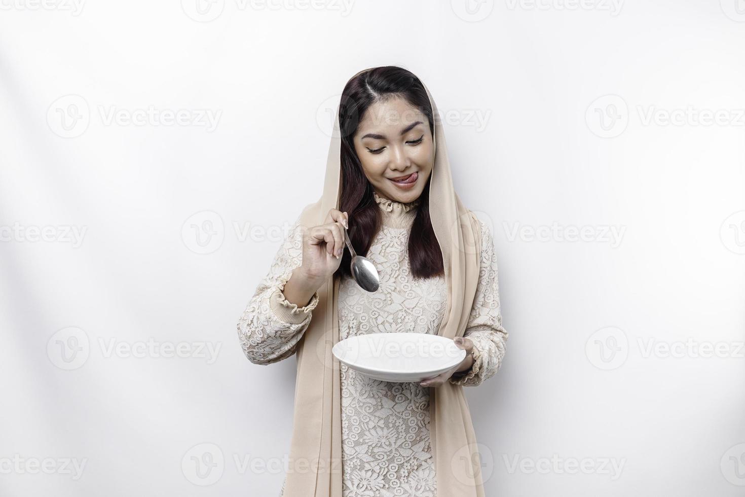 ett asiatisk muslim kvinna är fasta och hungrig och innehav redskap bestick medan ser åt sidan tänkande handla om Vad till äta foto