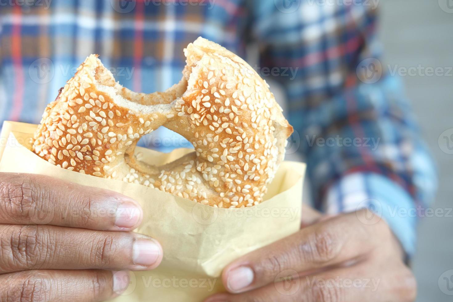 person som äter en sesamfrö bagel foto