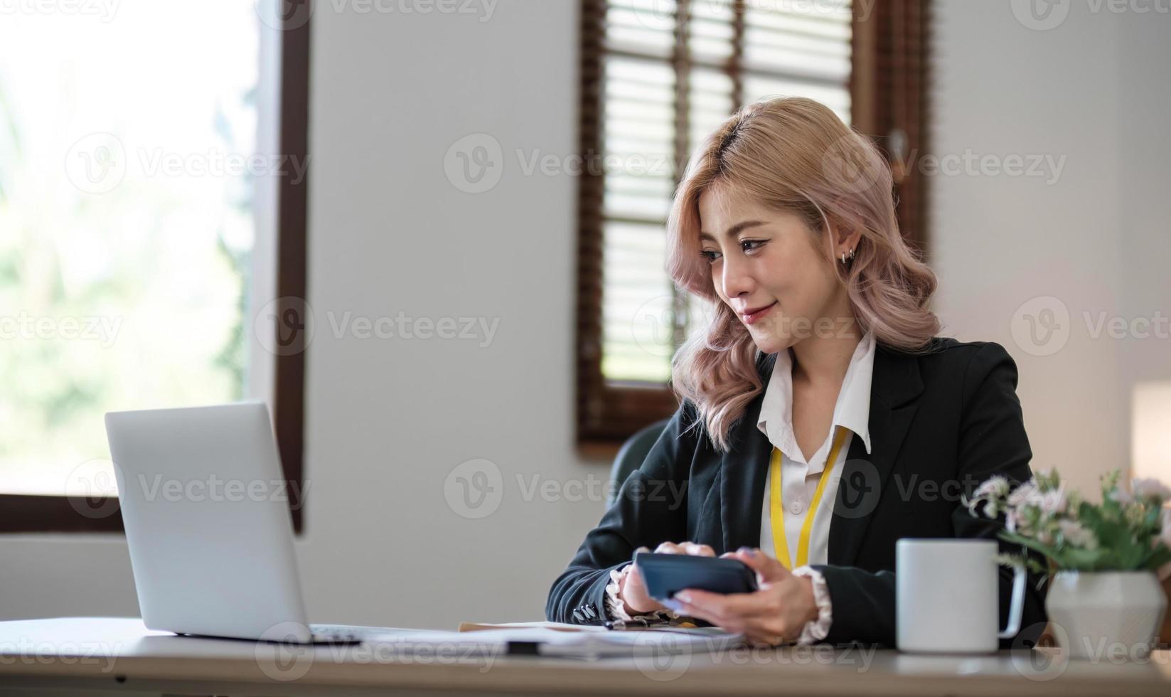 affärskvinna som använder miniräknare för matematikfinansiering på träbord i kontor och affärsarbetsbakgrund, skatt, redovisning, statistik och analytisk forskningskoncept foto