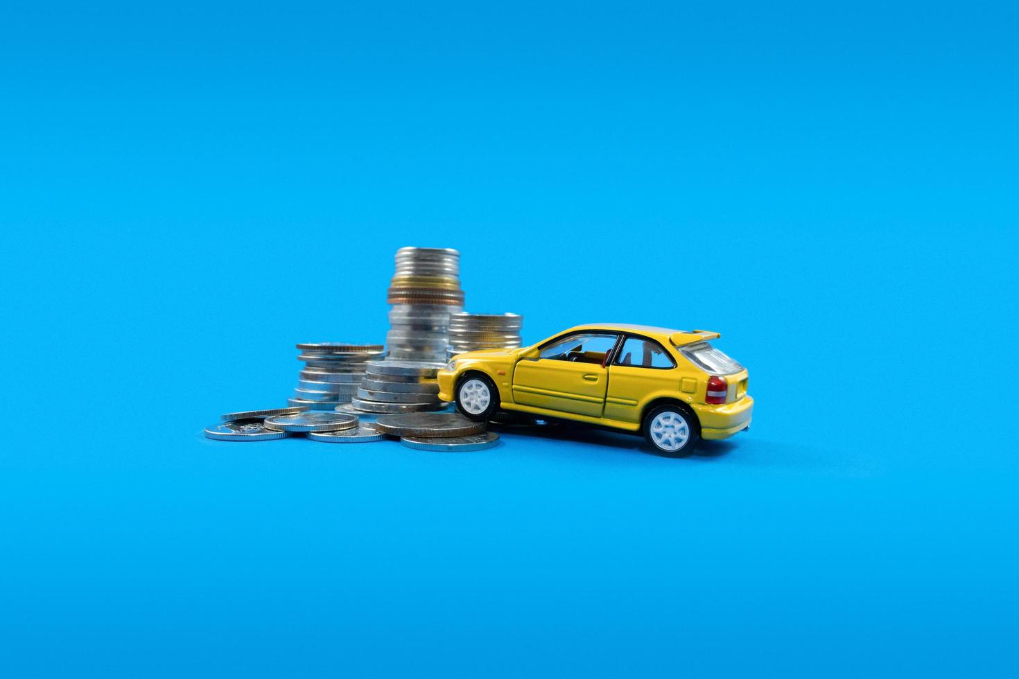 en gul leksak bil och lugg av mynt. begrepp av finansiell planera för uppköp en bil. foto