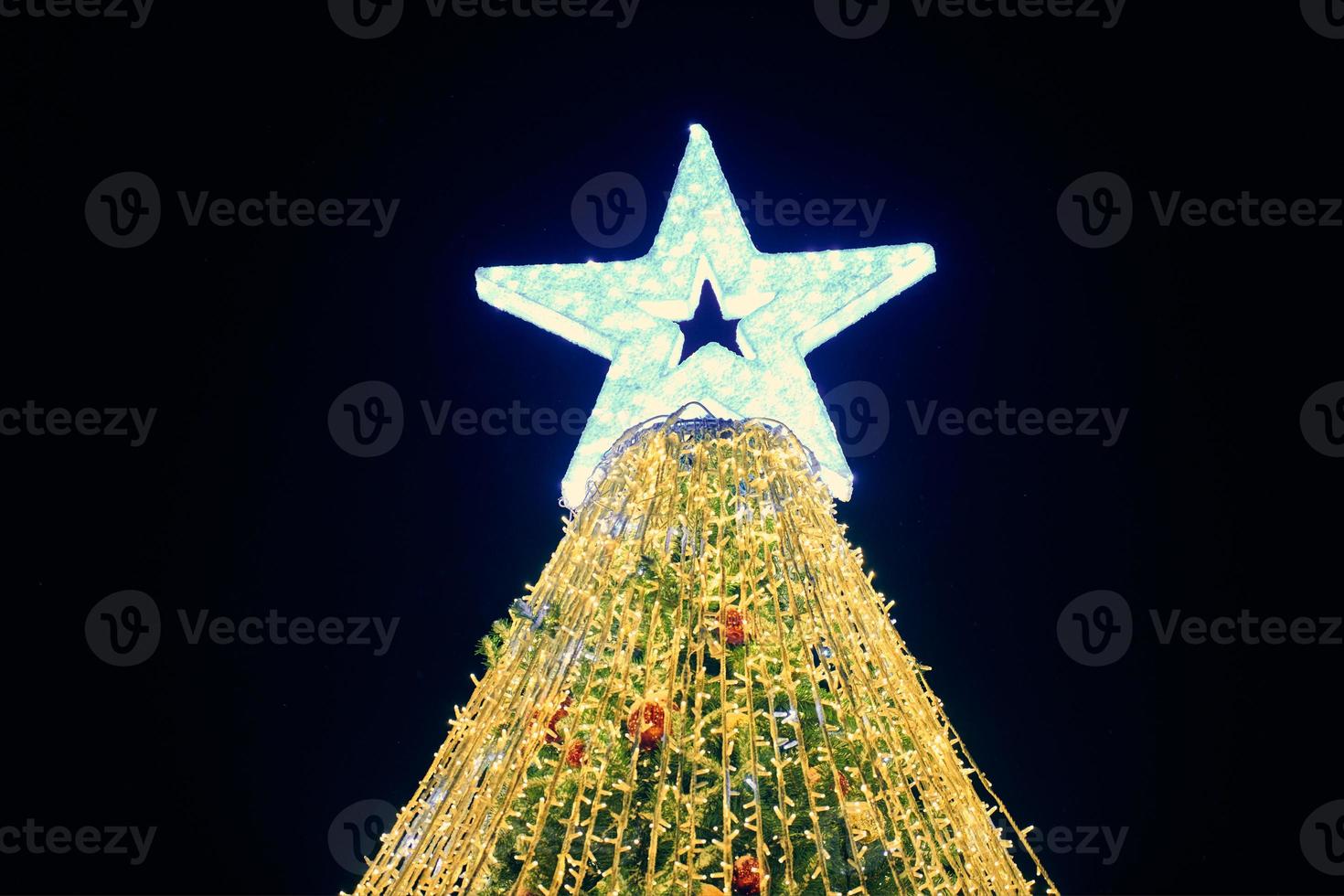 jul träd med stor vit stjärna topper dekorerad gul kransar och färgrik dekorativ lökar foto