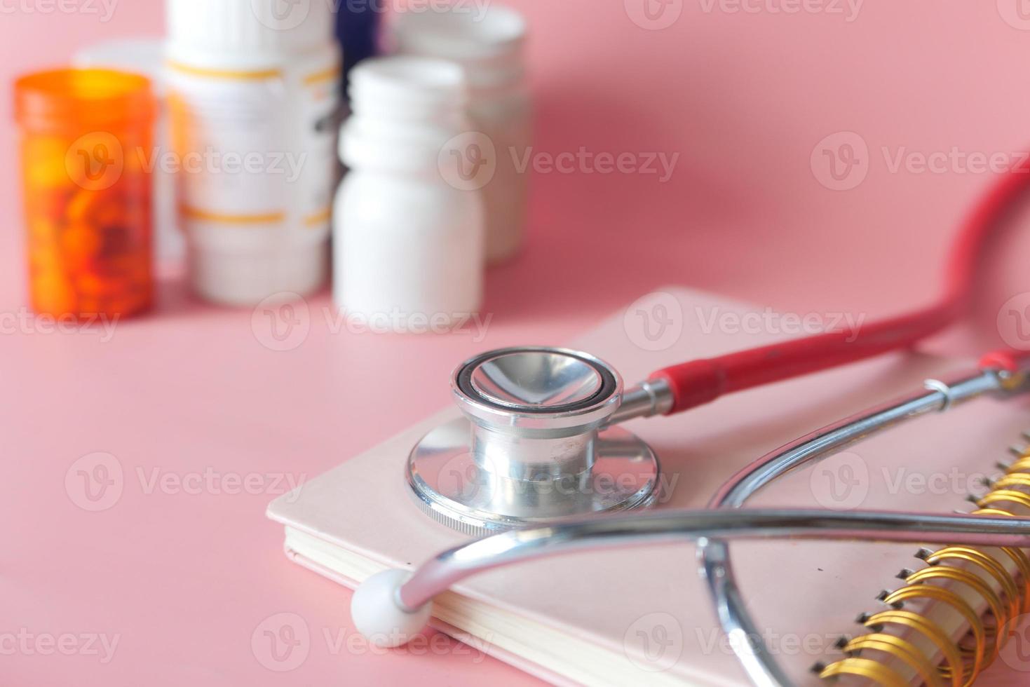 stetoskop och pillerbehållare på rosa bakgrund foto