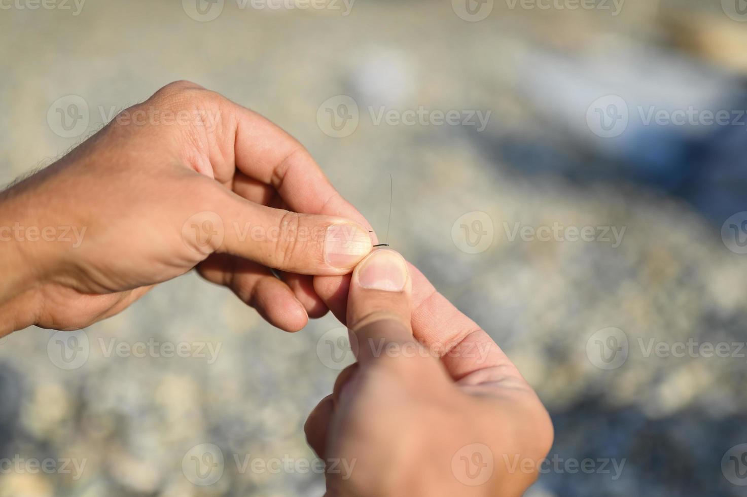 mans händer som binder en fiskelinje på en fiskekrok foto