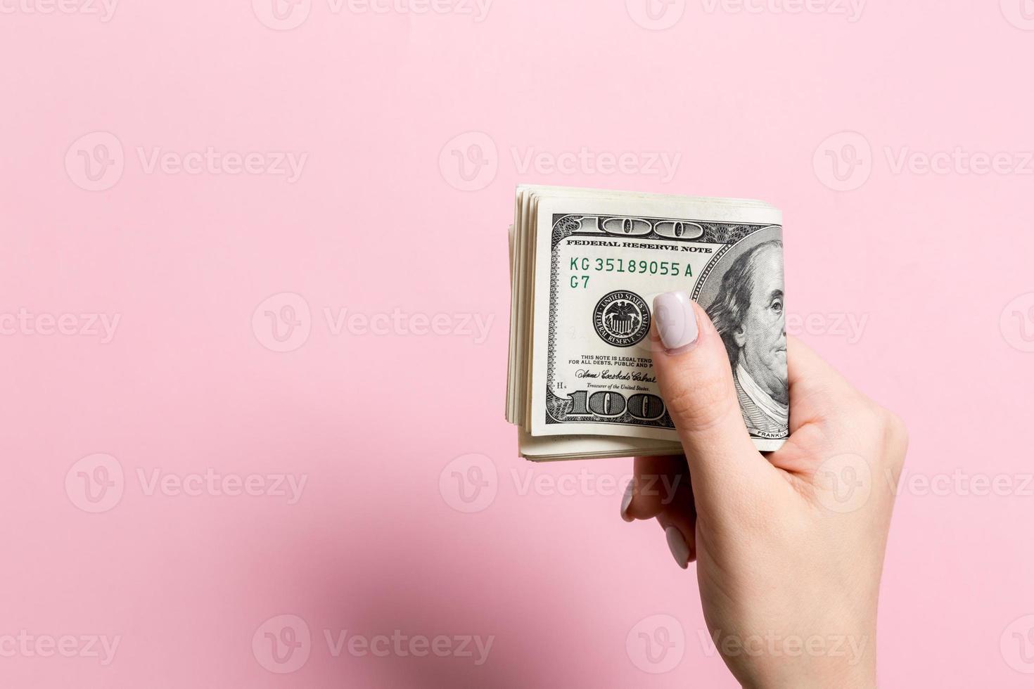 topp se av kvinna hand innehav en packa av pengar på färgrik bakgrund. ett hundra dollar. företag begrepp med tömma Plats för din design. välgörenhet och tips begrepp foto