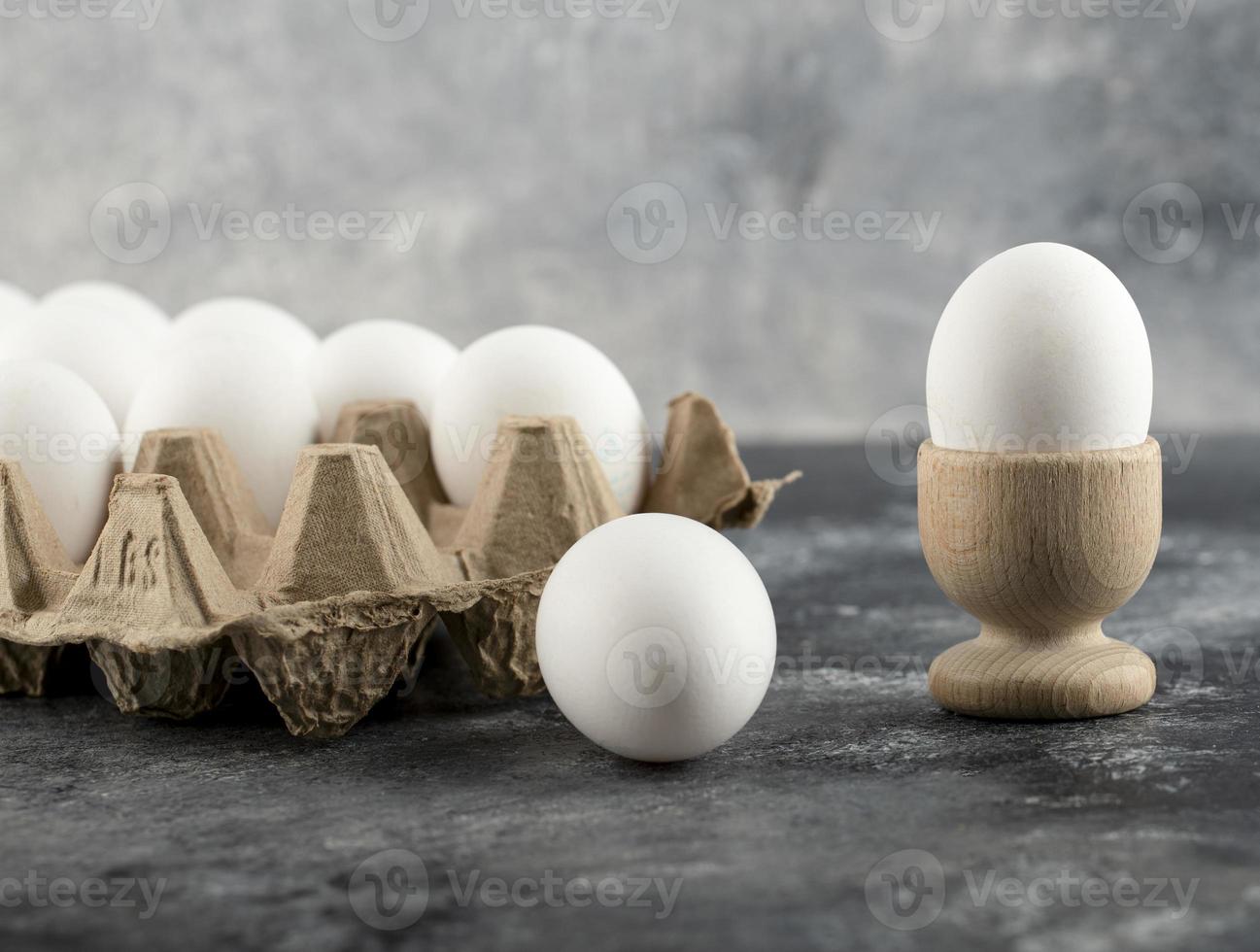 rå kycklingägg i en äggkopp med en ägglåda på marmorbakgrund foto