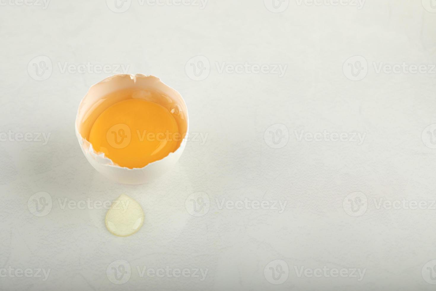 rå brutet ägg på en vit bakgrund foto