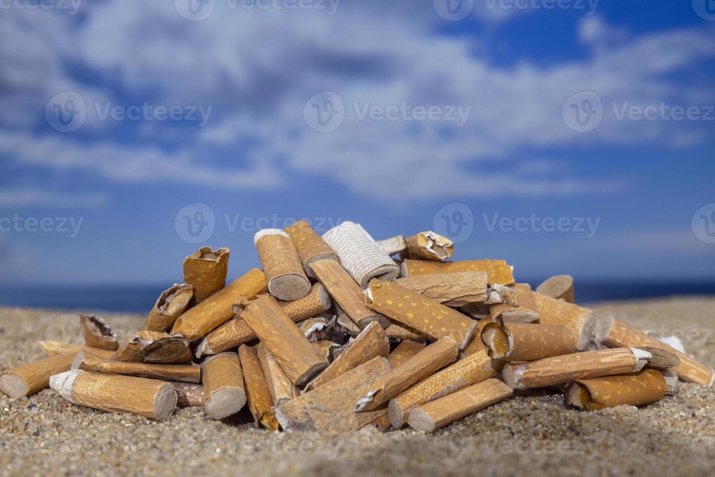 cigarett stubbar tappade och vänster i en lugg på en skön strand foto