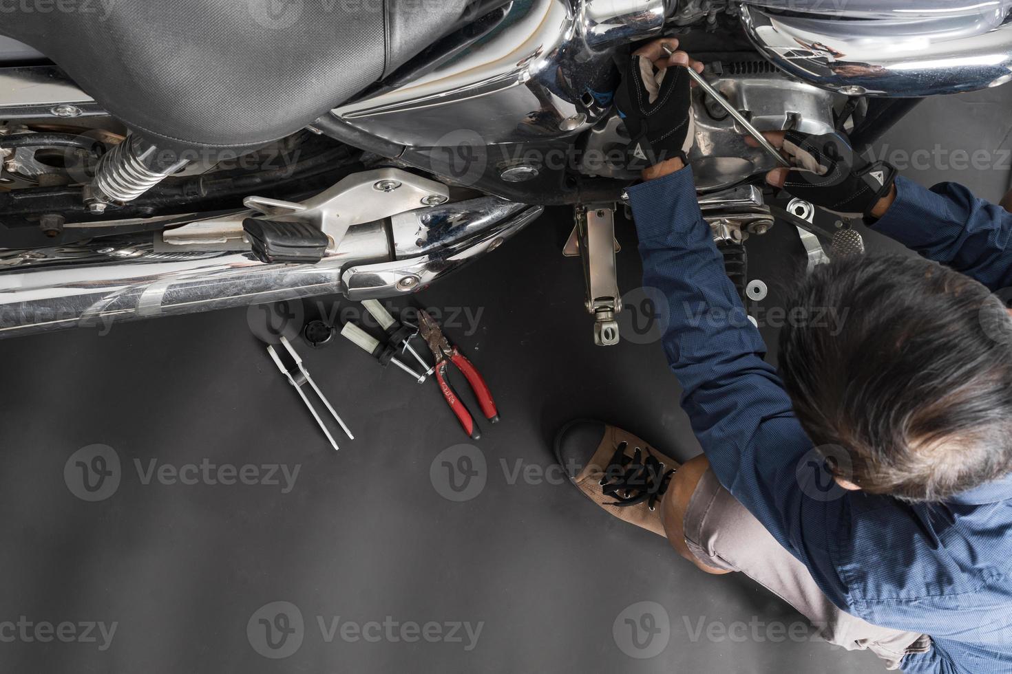 människor är reparation en motorcykel använda sig av en rycka och en skruvmejsel till arbete foto