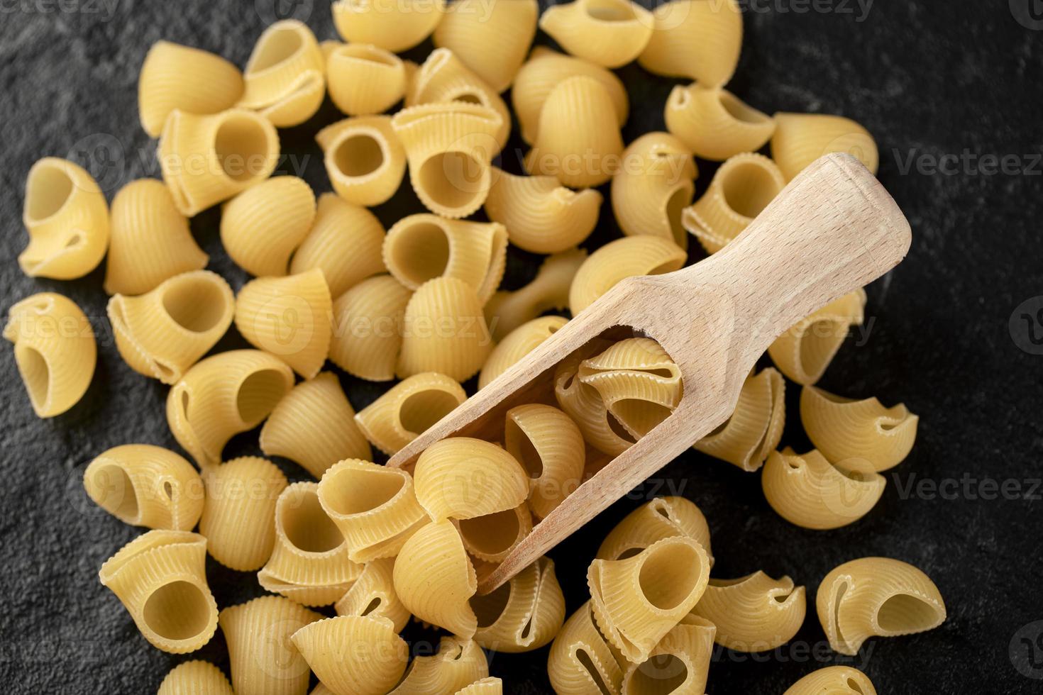 rå snäckskalformad pasta på svart bakgrund foto