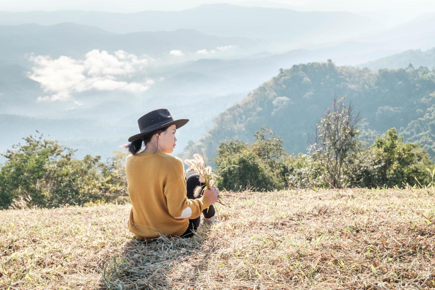 kvinna som håller ris medan du sitter på ett berg foto