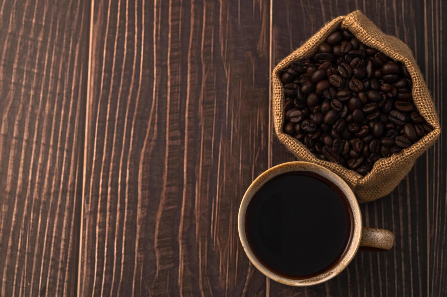 en kaffemugg och kaffebönor på ett träbord, älskar kaffekoncept foto
