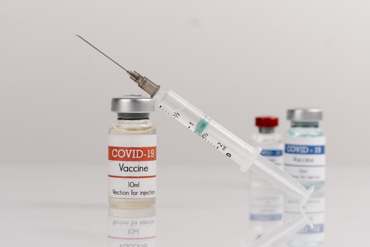 covid-19 vaccinflaskor med spruta på vit bakgrund foto