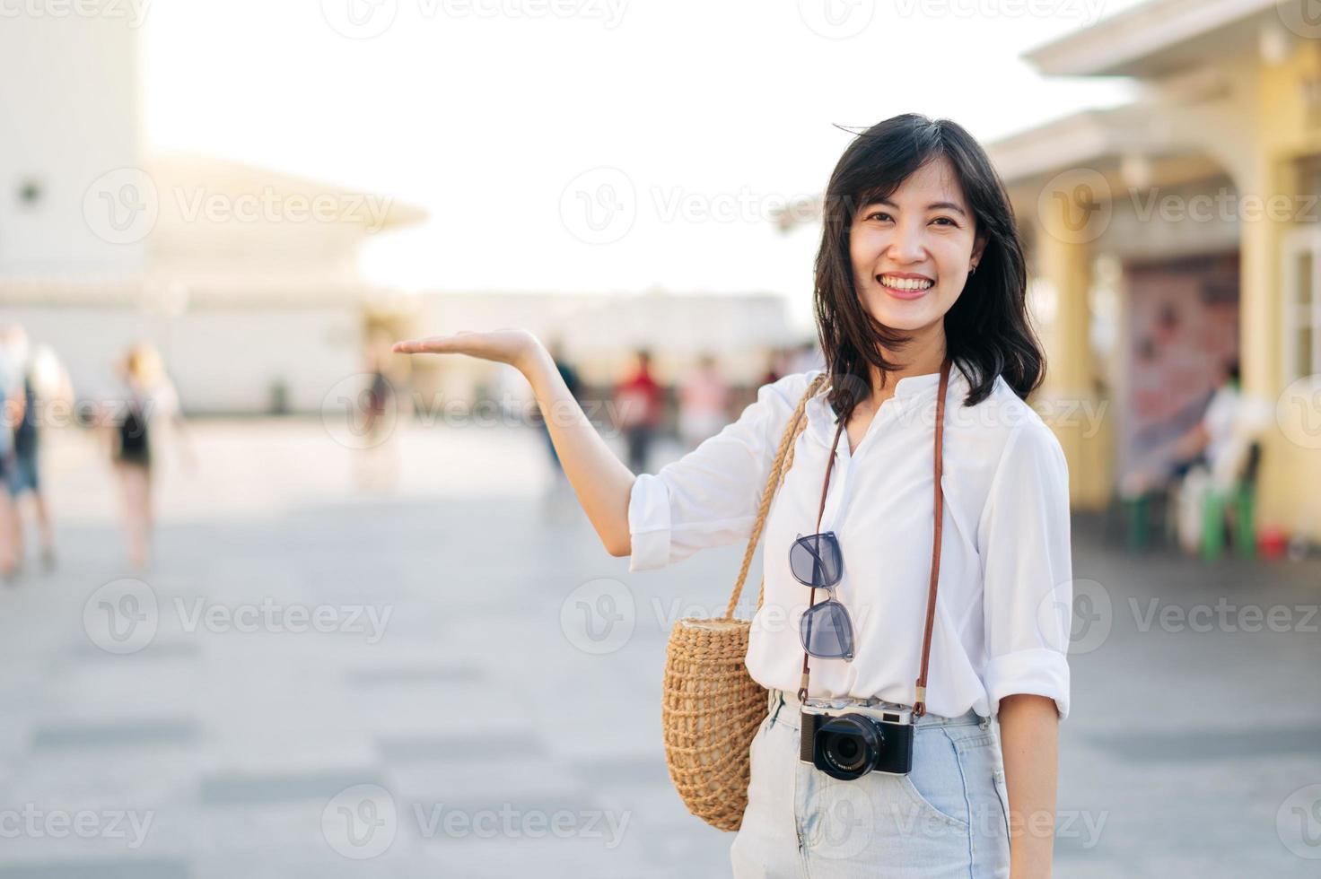 porträtt skön asiatisk kvinna resande hand gestikulerar och ser på kamera medan utforska gata på sommar semester i Bangkok, thailand foto
