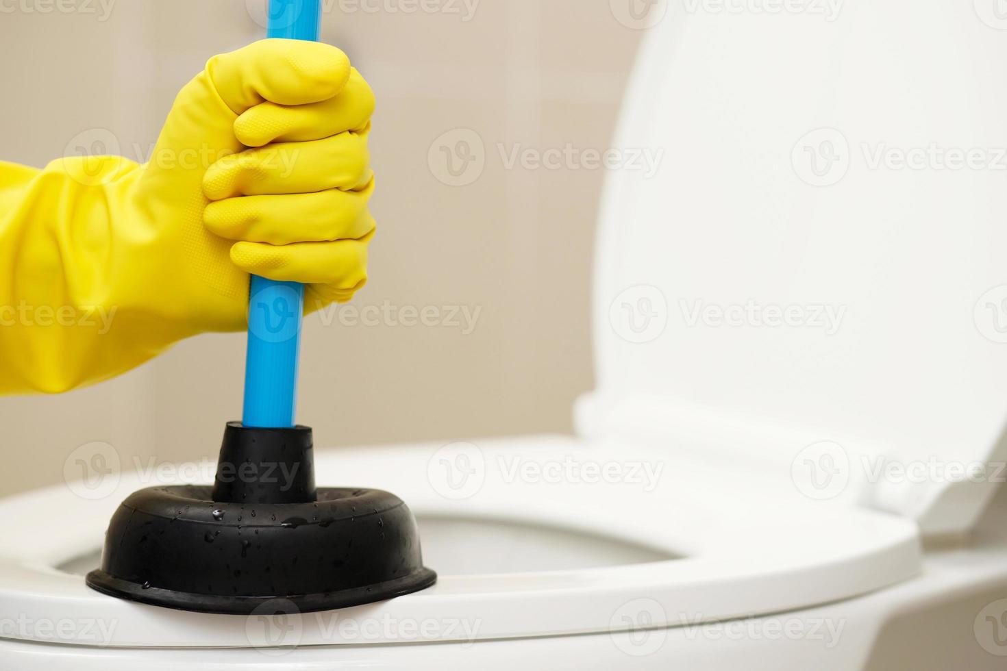 serviceman reparation toalett med hand kolven. igensatt toalett. foto