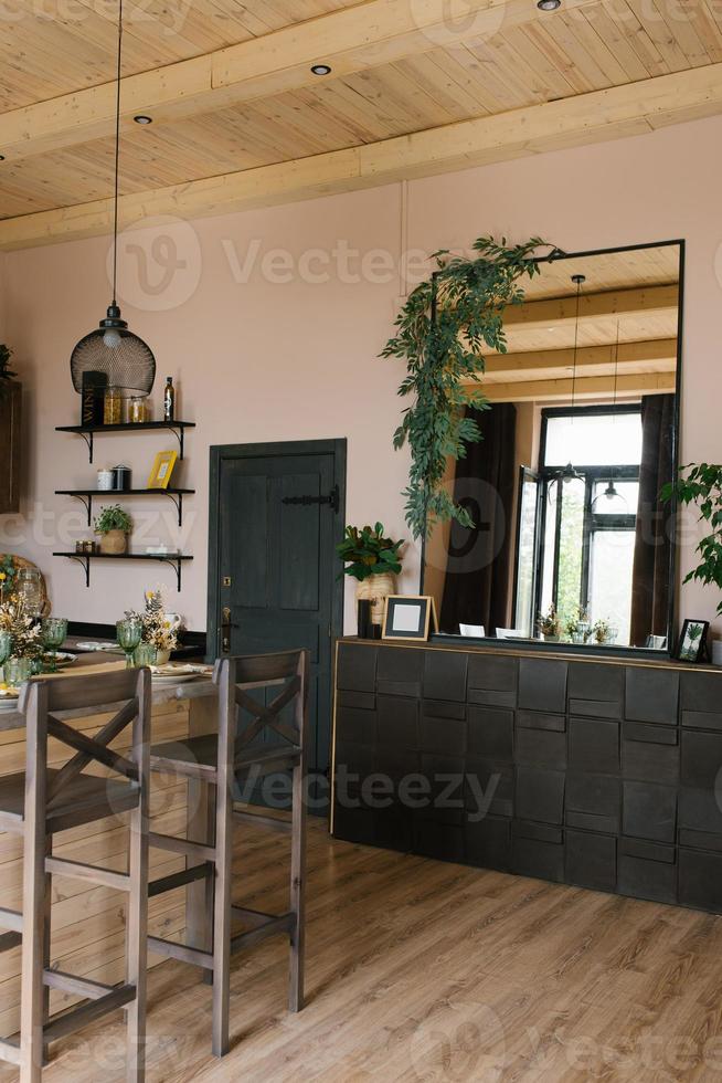 de interiör av en Land hus tillverkad av trä i de scandinavian stil. en bar tabell med stolar och en bröst av lådor med en stor spegel ovan den foto