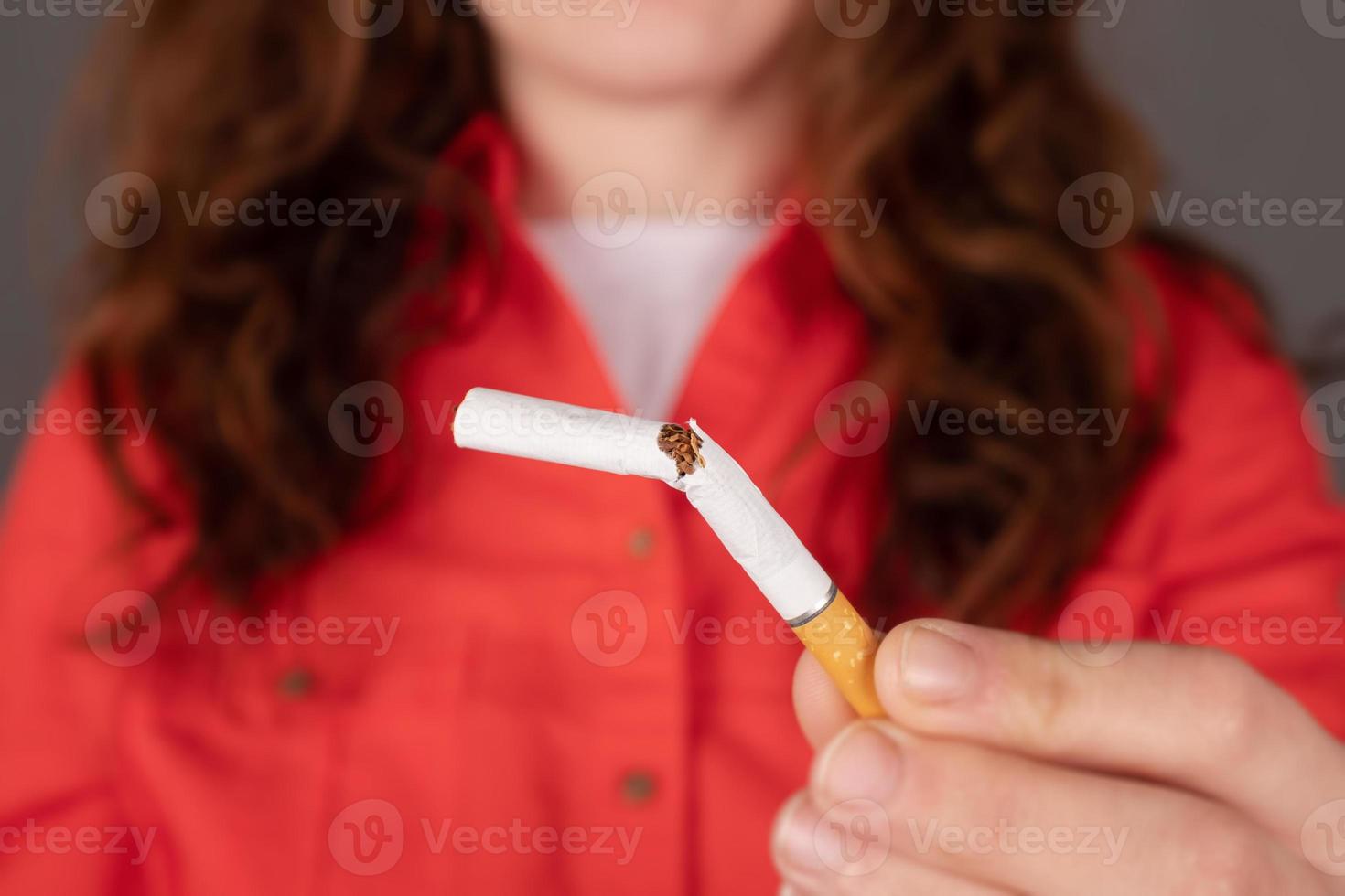 kvinna som håller en trasig cigarett foto