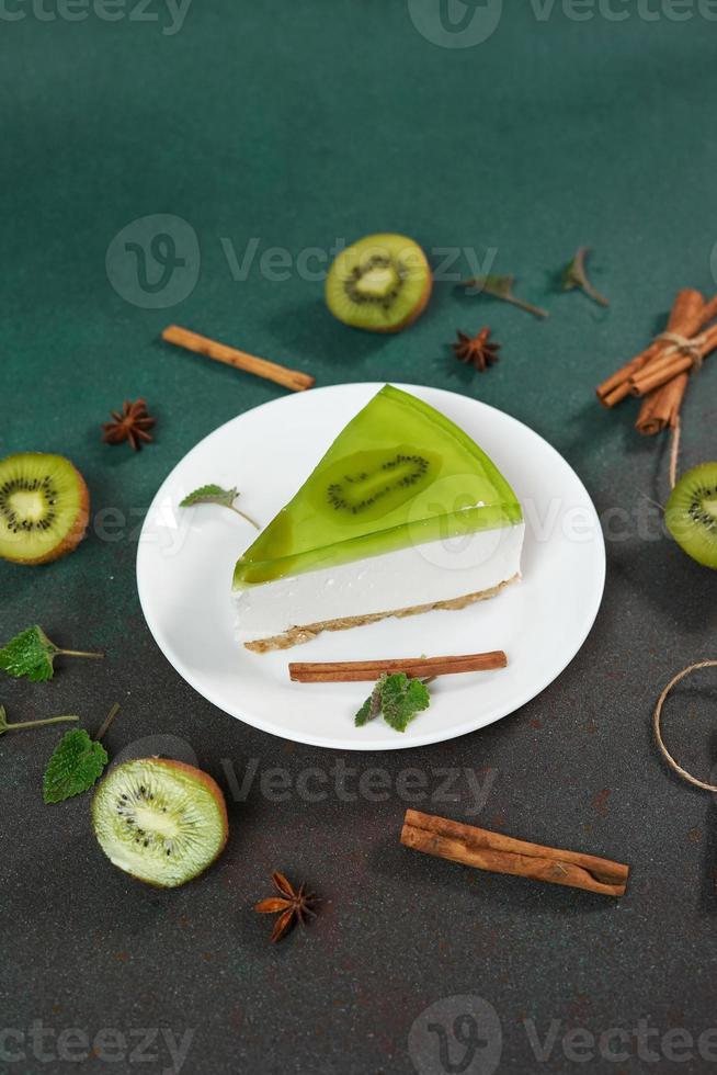 cheesecake med kiwi, kanel pinne och löv mynta på en grön bakgrund. kopia cpase för text foto