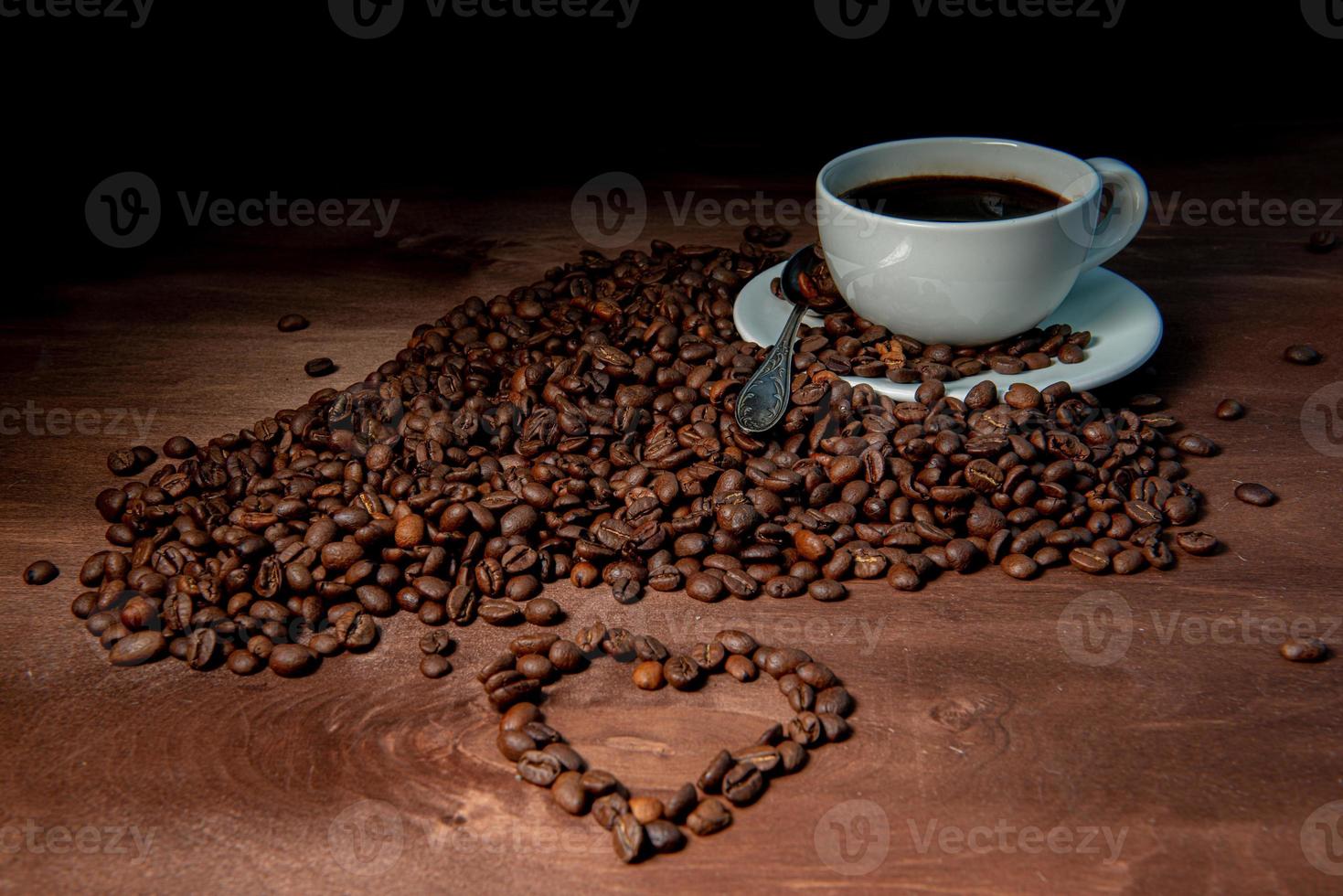 vitt kaffemugg och kaffebönor på den mörka träbakgrunden foto