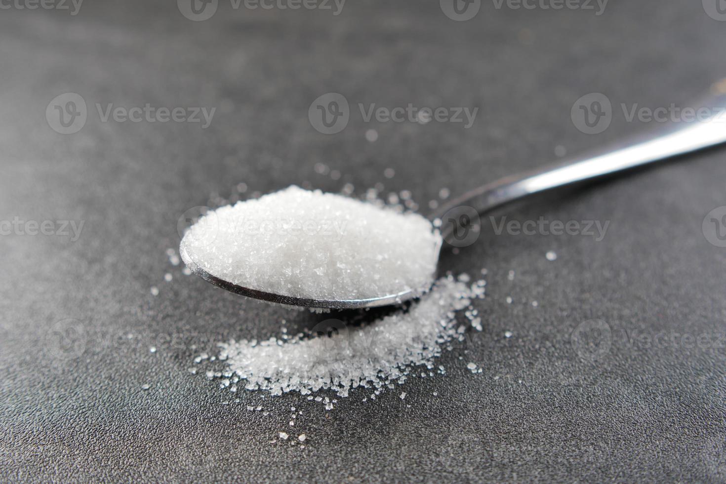 vit socker på en silver- sked på tabell foto