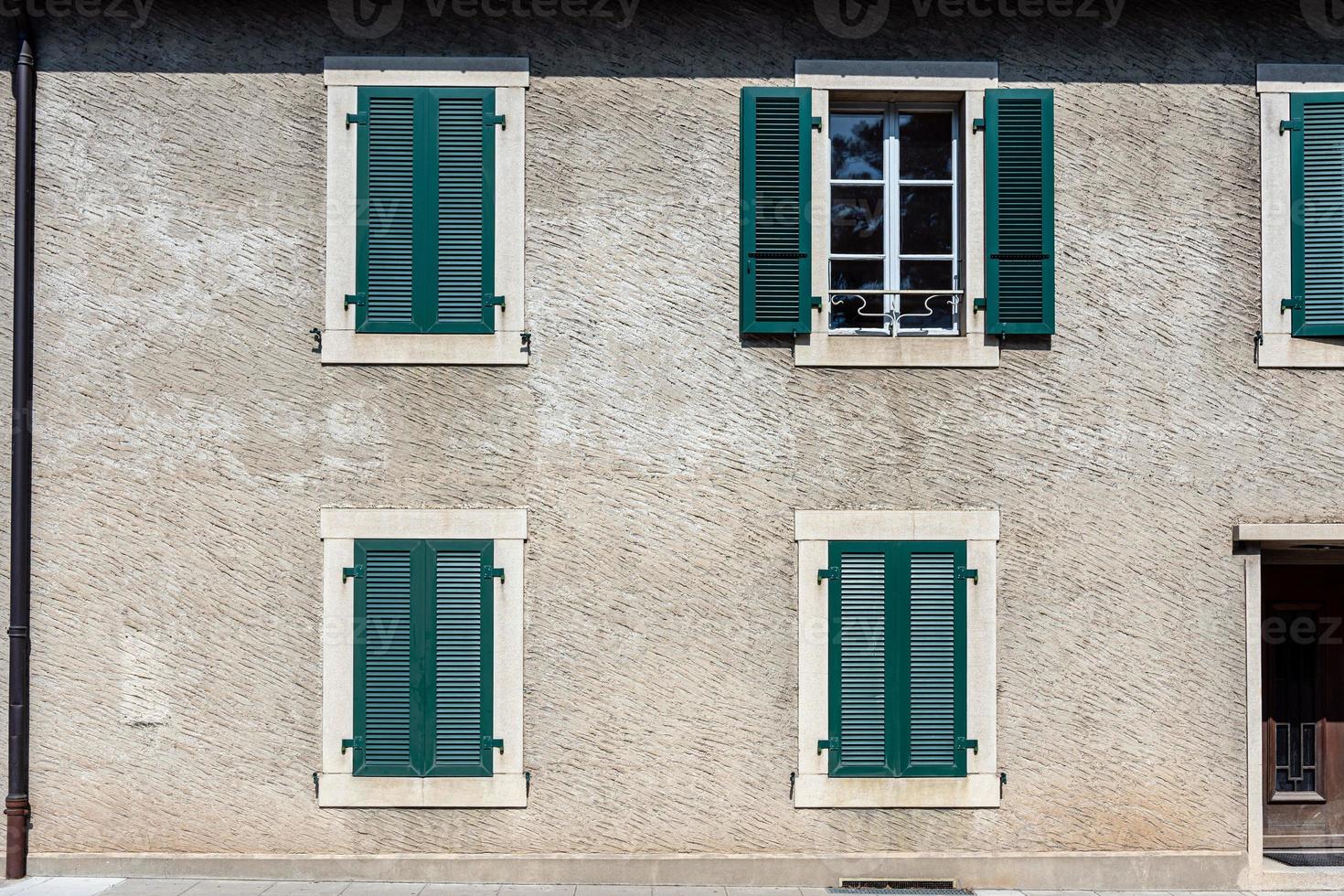 fasad av ett stenhus med gröna fönsterluckor foto