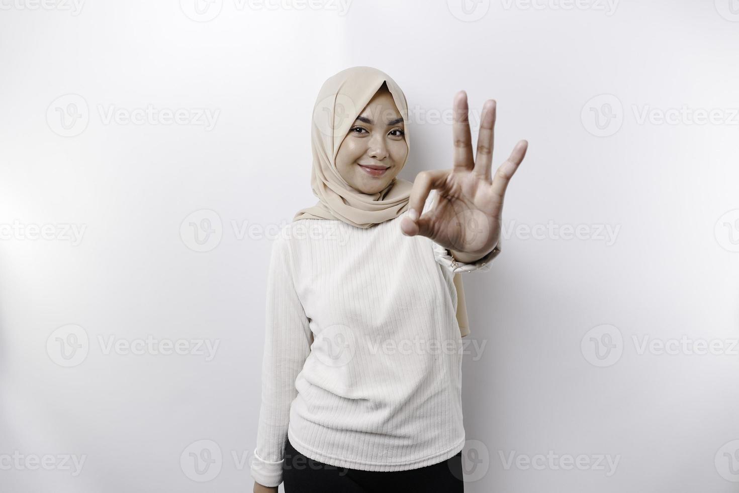 en leende asiatisk muslim kvinna, ger ett ok hand gest isolerat över vit bakgrund foto
