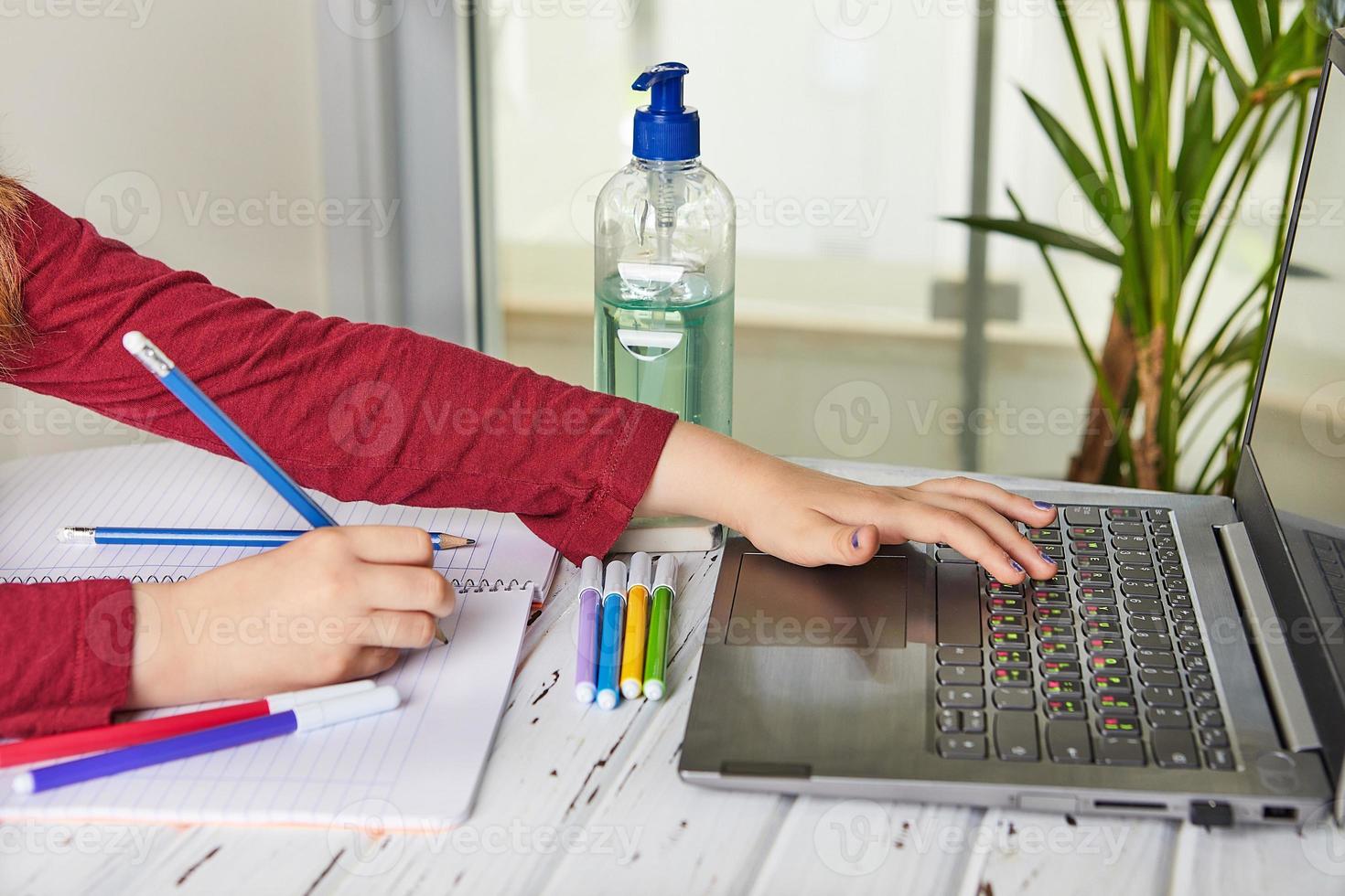 skolflicka som studerar hemma med en bärbar dator och gör skolläxor foto