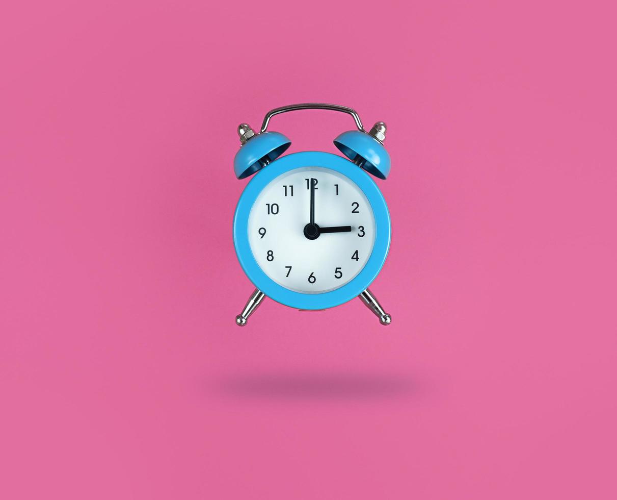 svävande blå väckarklocka på rosa bakgrund foto