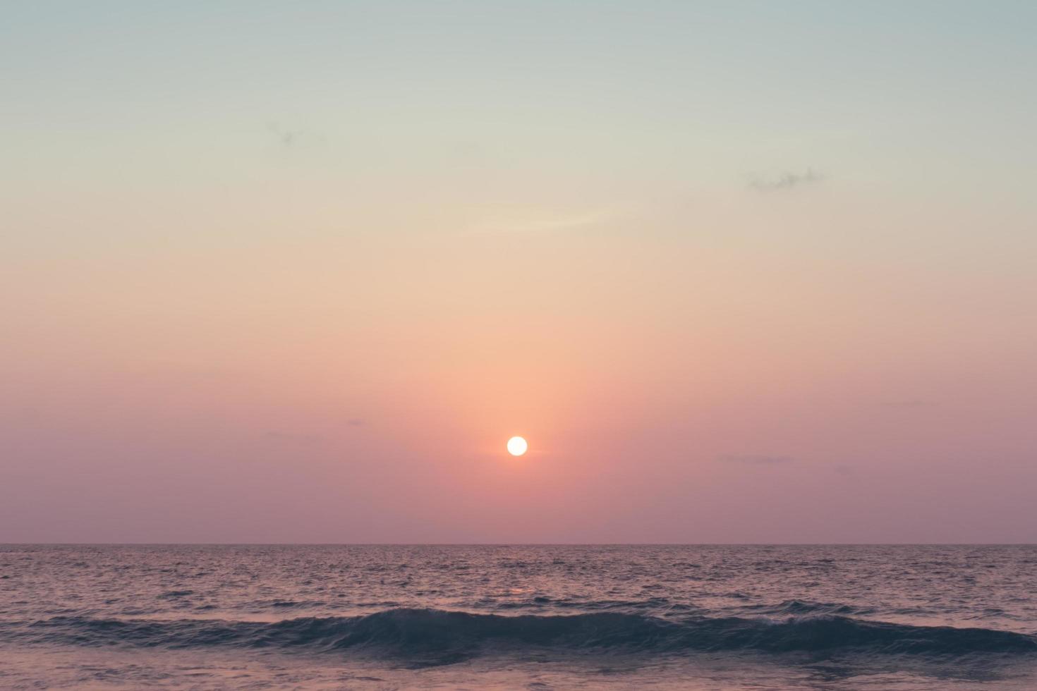 färgglada havsvågor under en rosa soluppgång eller solnedgång med solen i bakgrunden foto