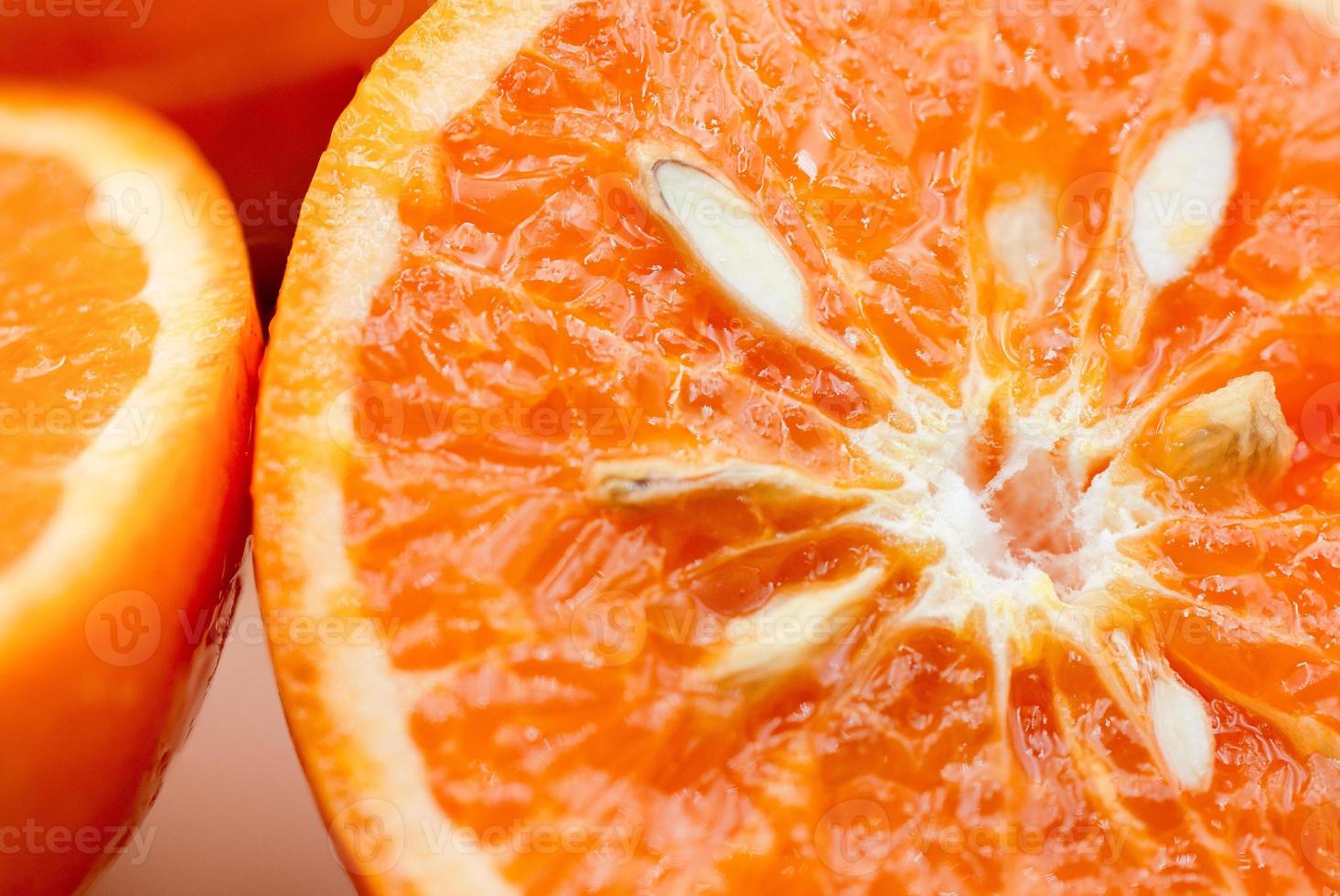 apelsiner på rosa bakgrund. ett orange är skära i halv, de Övrig är hela. foto