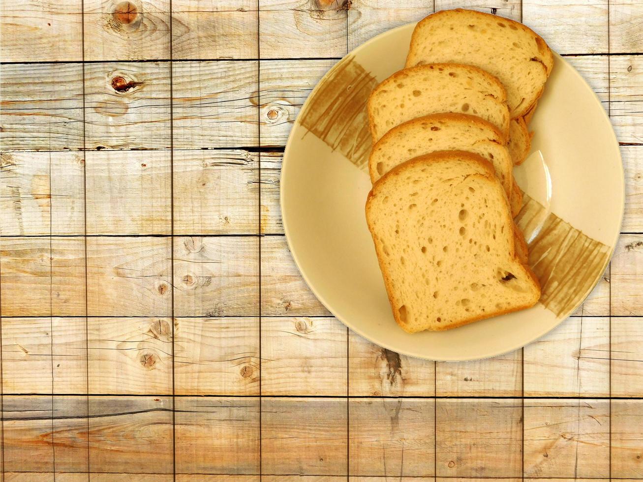 skivat bröd på en keramisk tallrik på en träbordbakgrund foto