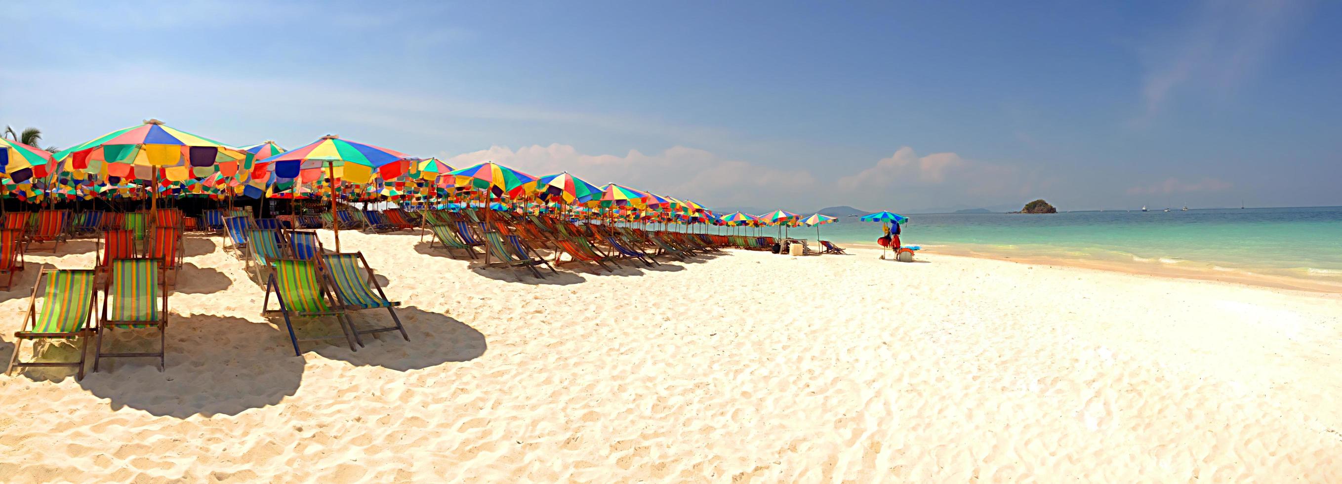 panorama av färgglada paraplyer och fåtöljer på stranden foto