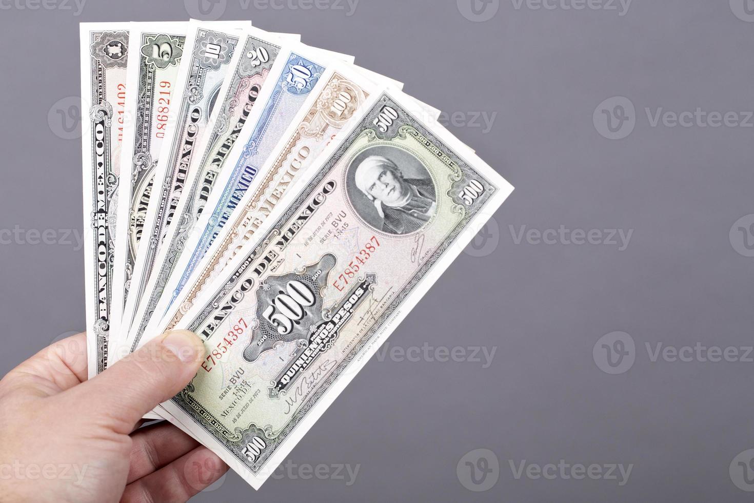 gammal mexikansk pengar i de hand på en grå bakgrund foto