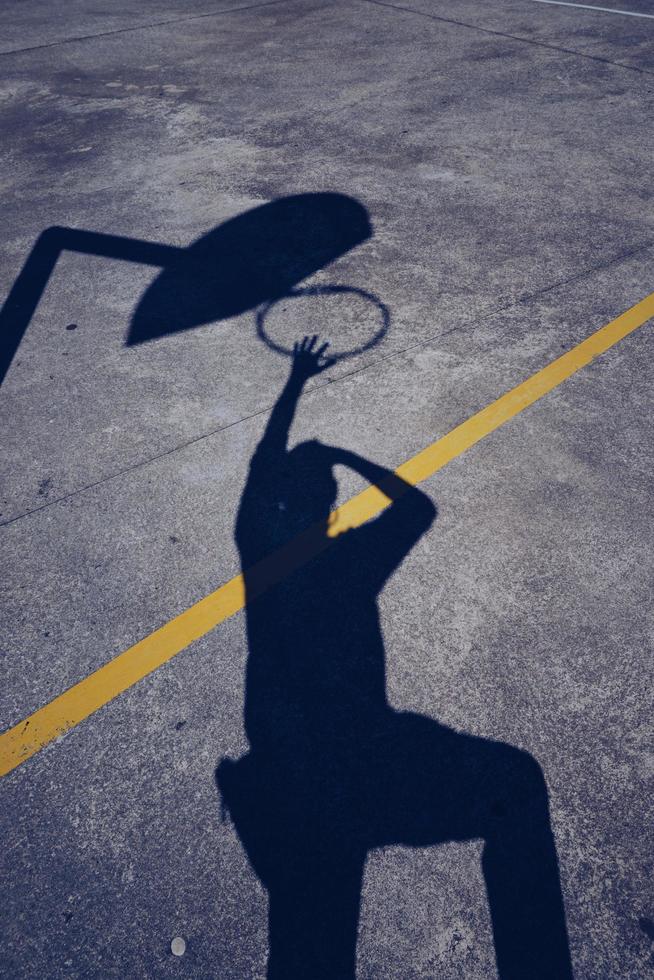 mans skugga på marken och spela basket foto