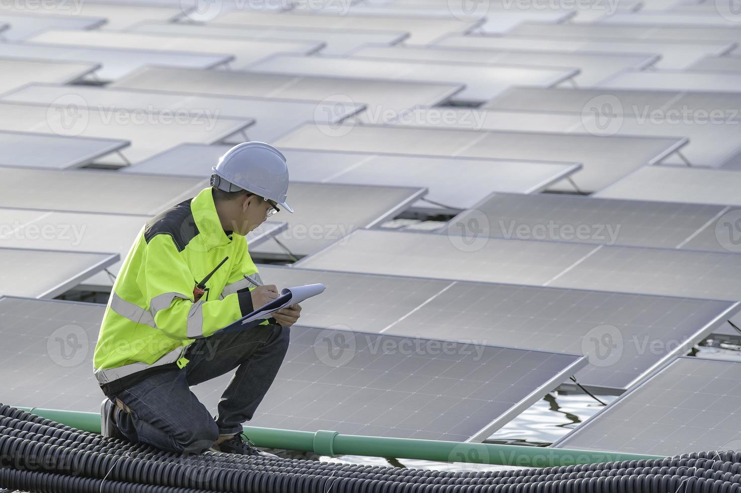 asiatisk ingenjör arbetssätt på flytande sol- kraft anläggning, förnybar energi, tekniker och investerare sol- paneler kontroll de paneler på sol- energi installation foto