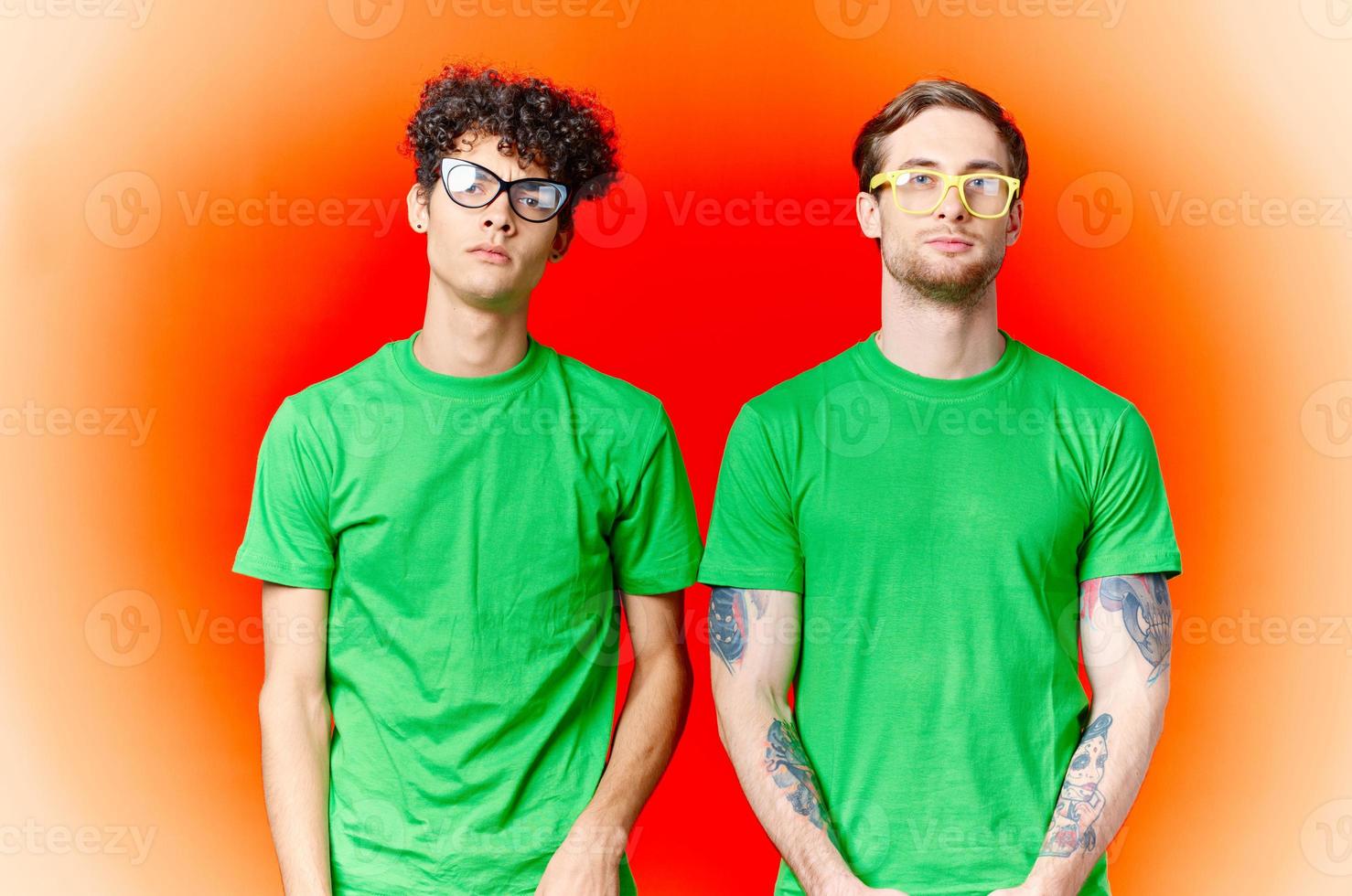 två vänner är stående sida förbi sida i grön t-tröjor med glasögon foto
