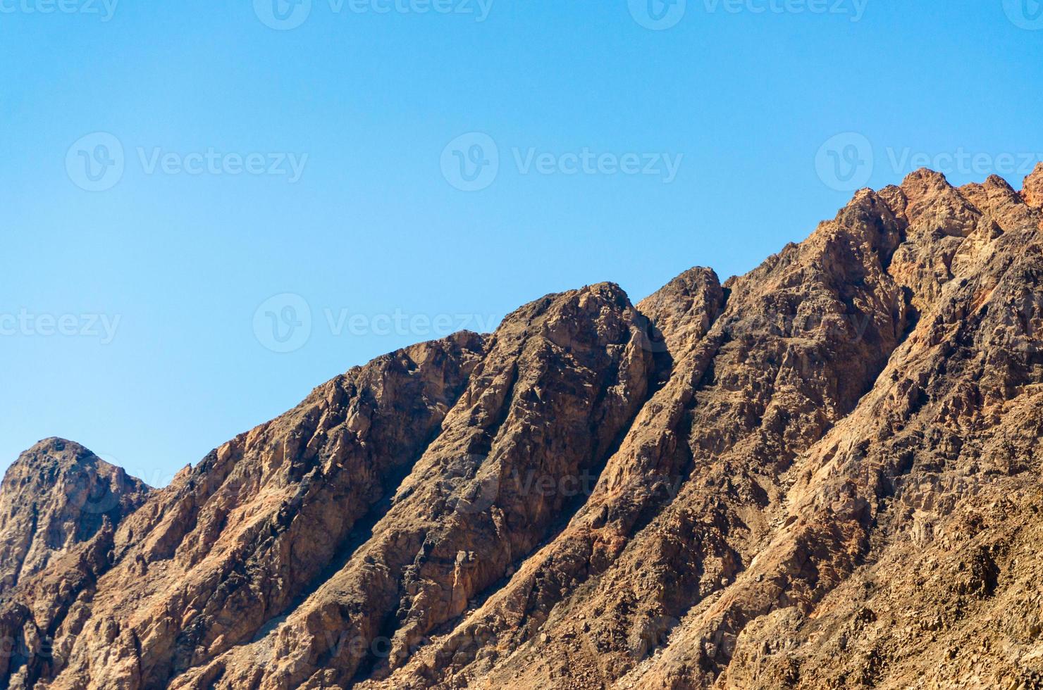 toppar av steniga berg mot en blå himmel i Egypten foto