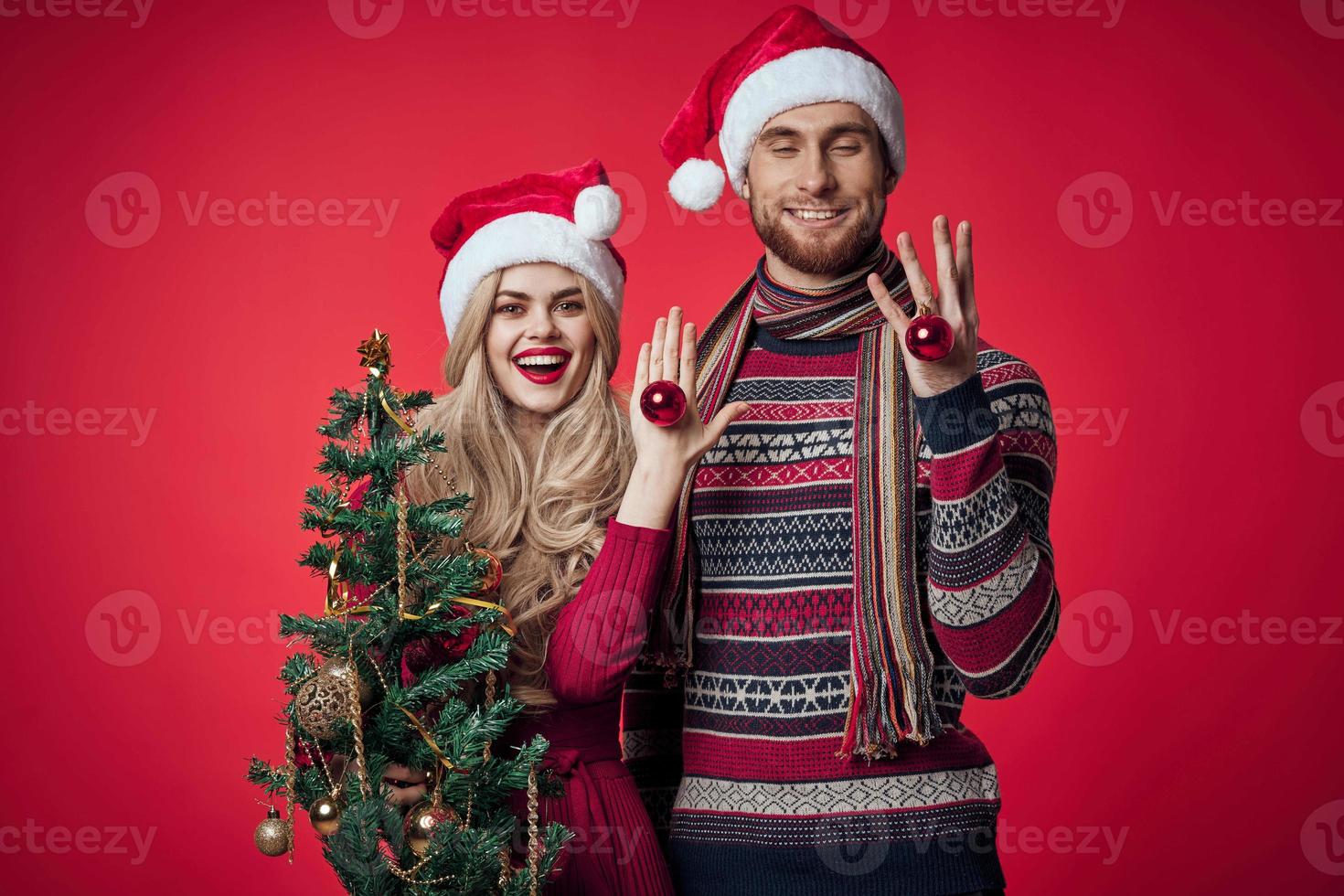 söt ung par innehav jul träd leksaker dekoration röd bakgrund foto