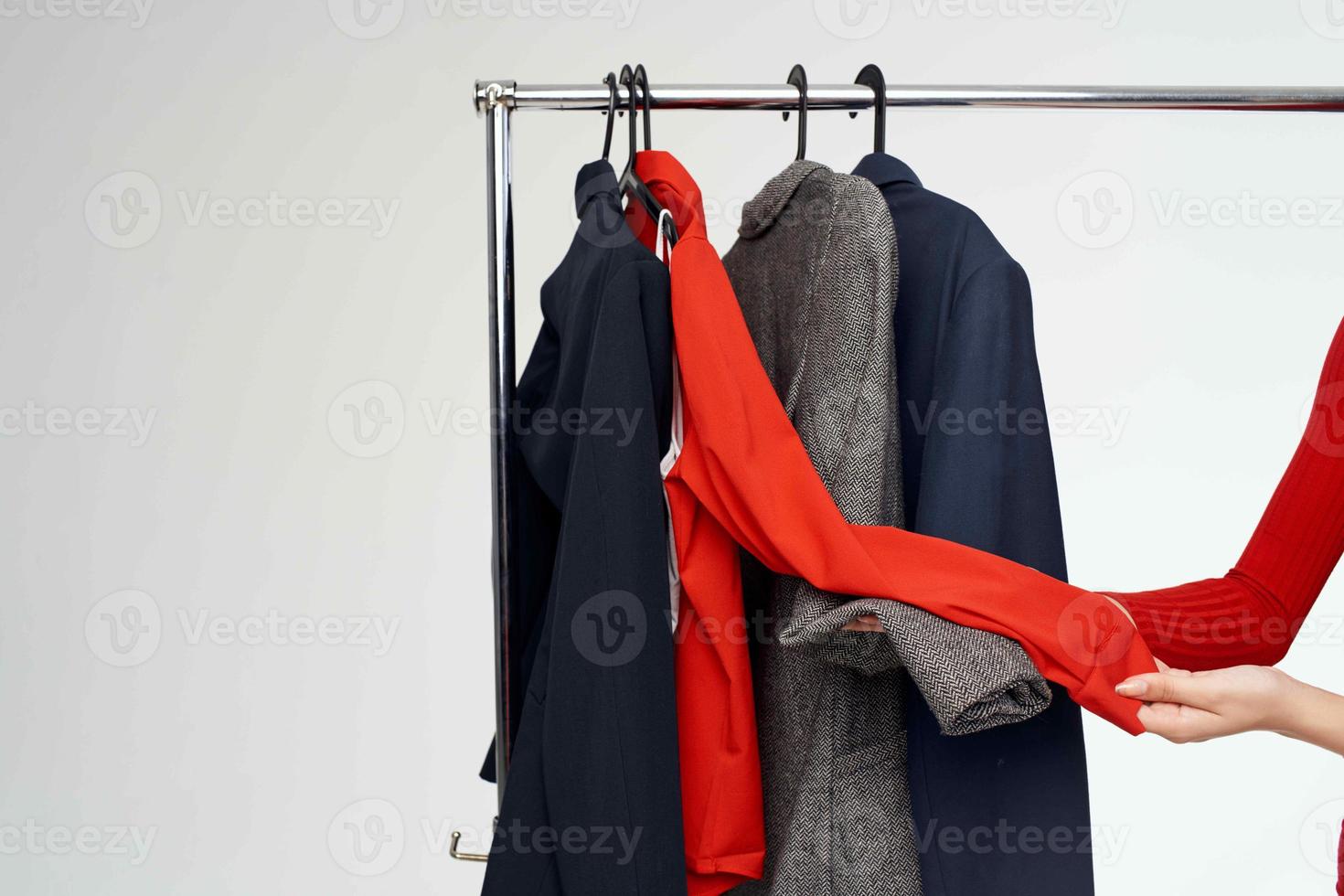 skön kvinna i en röd jacka nära de garderob detaljhandeln ljus bakgrund foto