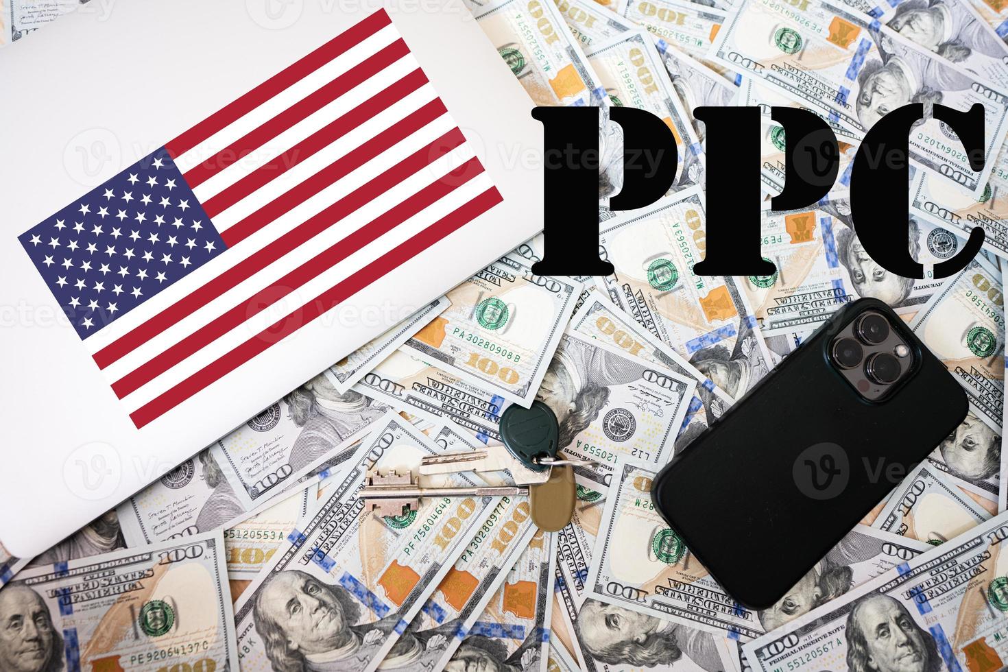 ppc. betala per klick begrepp. USA flagga, dollar pengar med nycklar, bärbar dator och telefon bakgrund. foto