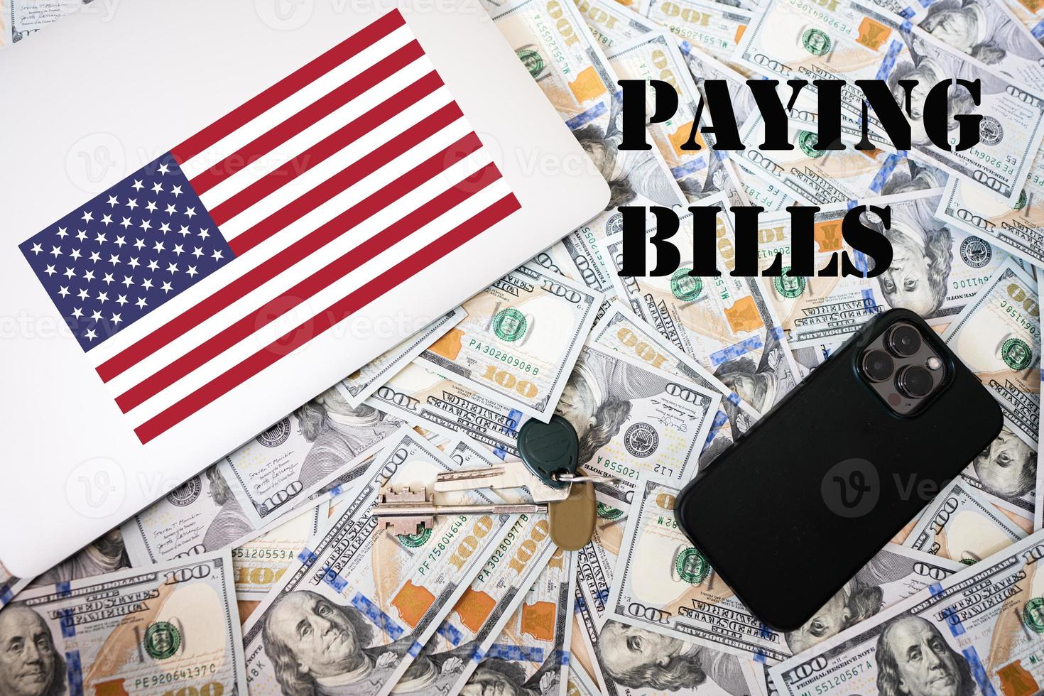 betalande räkningar begrepp. USA flagga, dollar pengar med nycklar, bärbar dator och telefon bakgrund. foto