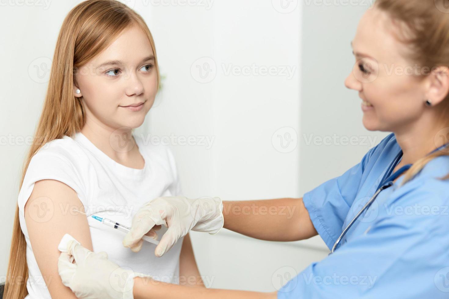 kvinna läkare ger ett injektion till en flicka i de hand av en sjukhus hälsa covid foto