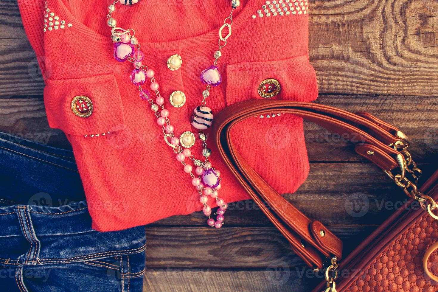 kvinnors Kläder och Tillbehör Tröja, jeans, handväska, pärlor på trä- bakgrund. tonad bild. foto