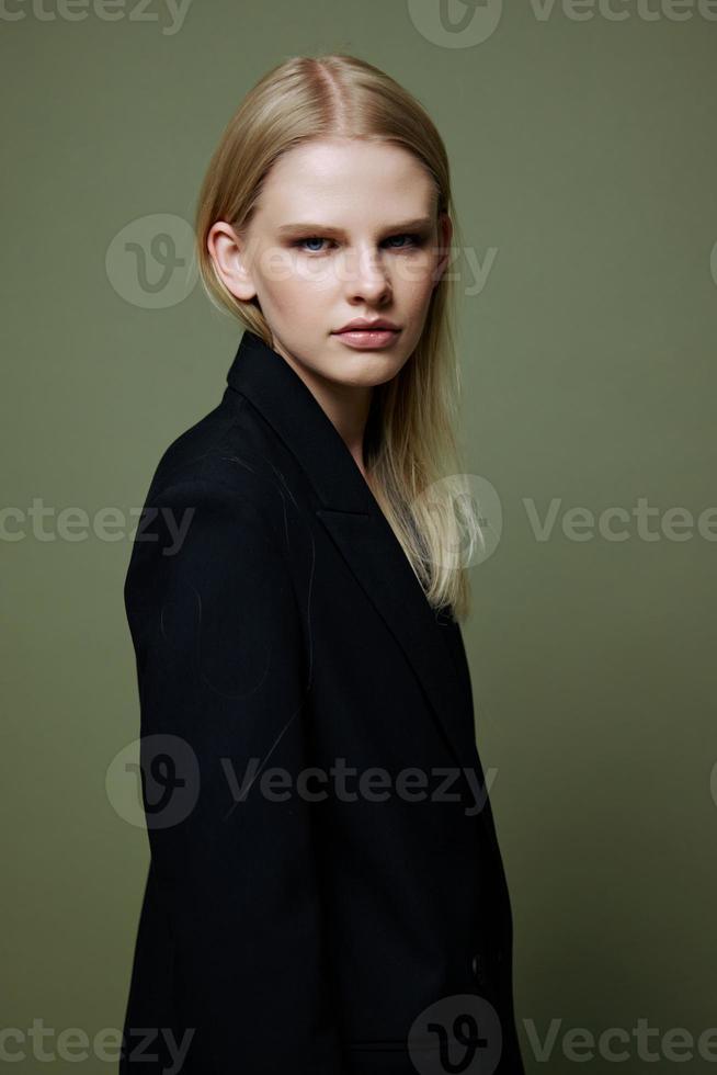 de ung modell vänder och utseende på de kamera över henne axel. Häftigt baner erbjudande. en flicka poser i isolering i en kostym i en studio med en grön bakgrund foto